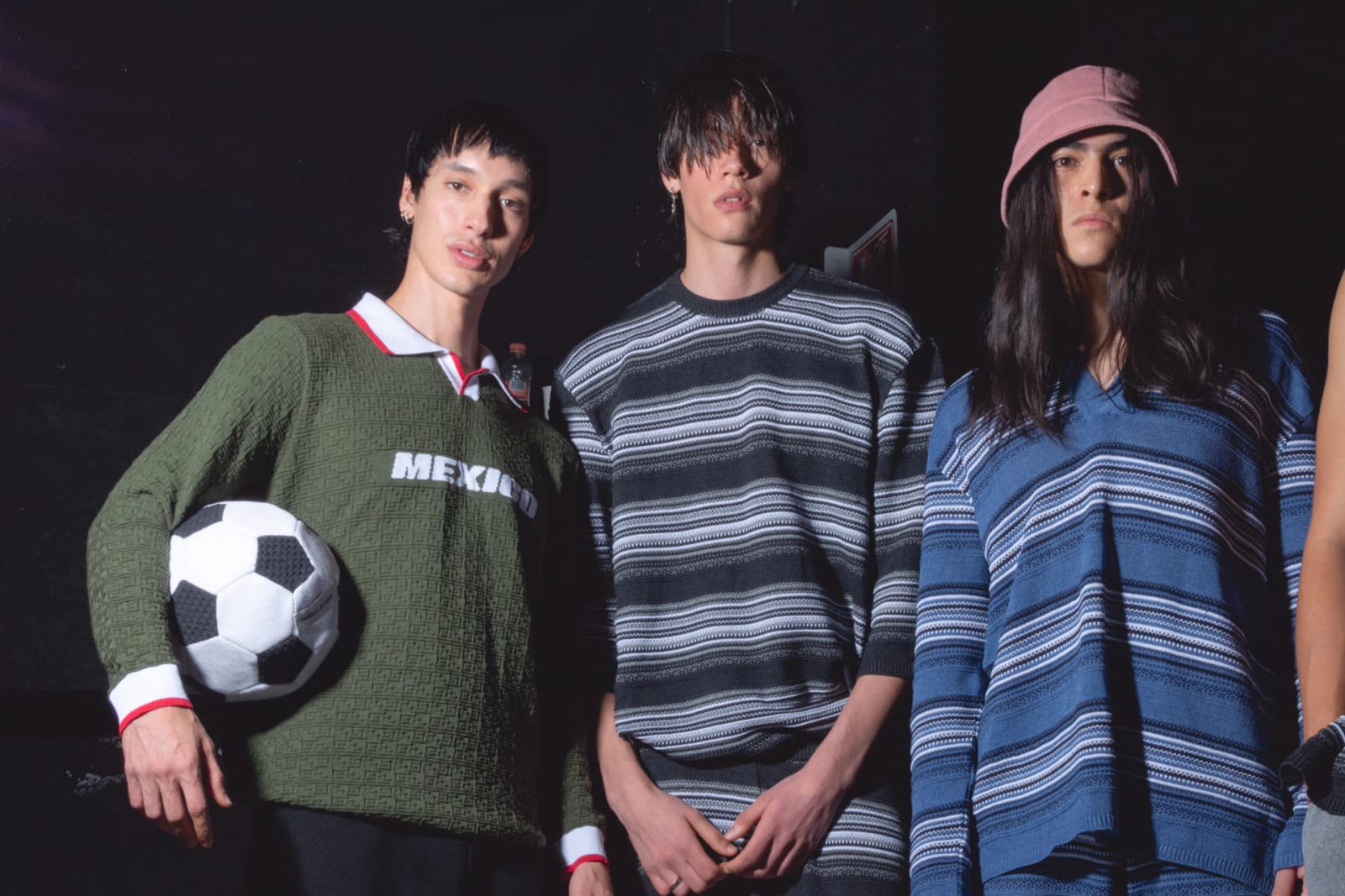 Tres modelos con prendas de tejido de punto de Fábrica de Punto; uno lleva la polo verde México 26 y un balón de futbol