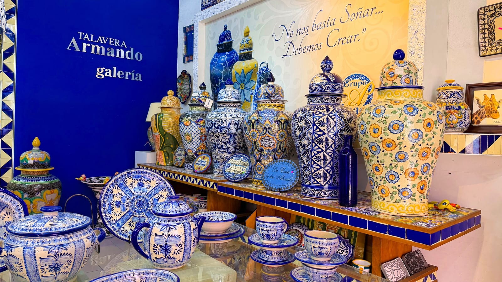 Galería de Talavera Armando en Puebla con tibores, vajillas y platones de talavera azul y amarilla frente al lema de la casa