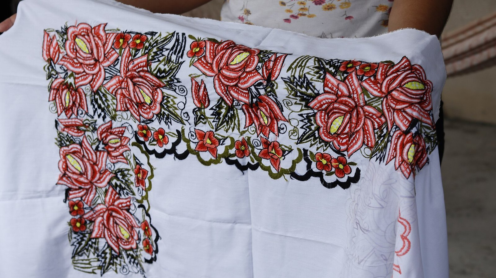 Tela blanca con bordado yucateco de flores rojas y hojas verdes