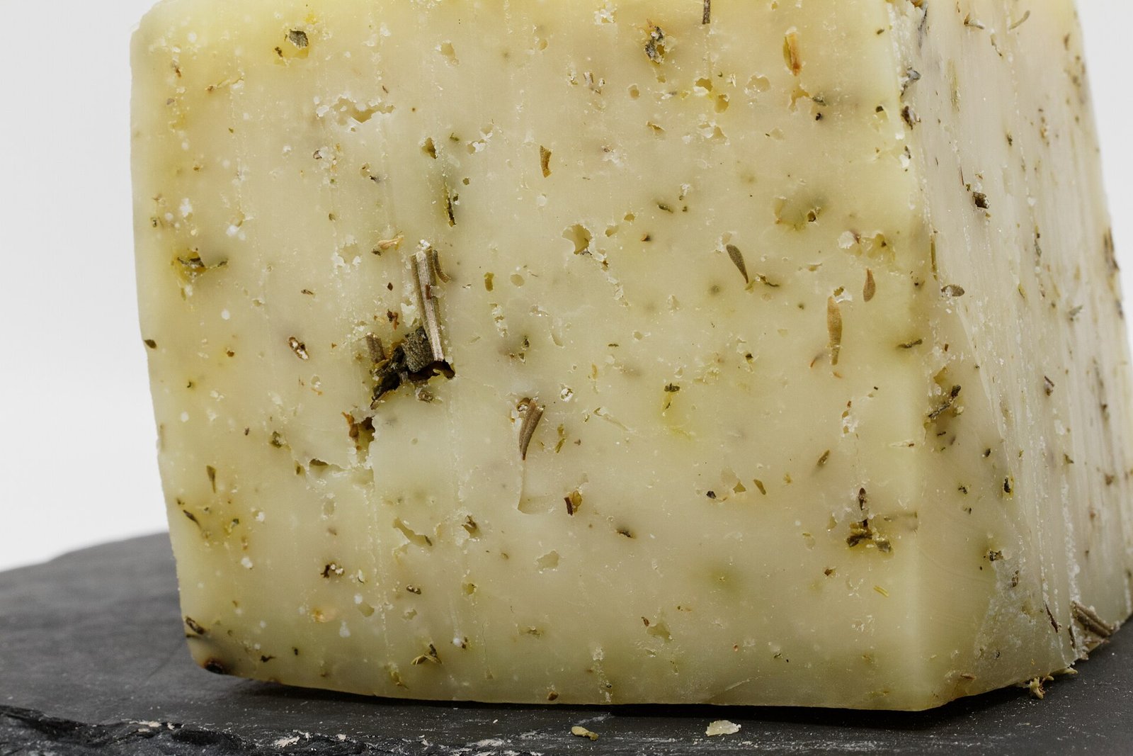 Cuña de queso semicurado de oveja con hierbas sobre una pizarra