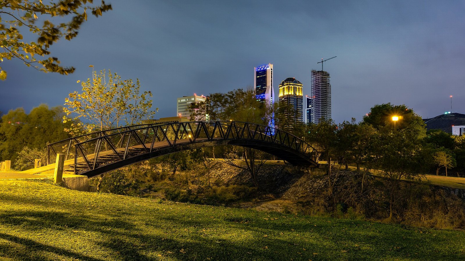 Puente peatonal del Parque Rufino Tamayo de noche, con edificios de San Pedro Garza García al fondo