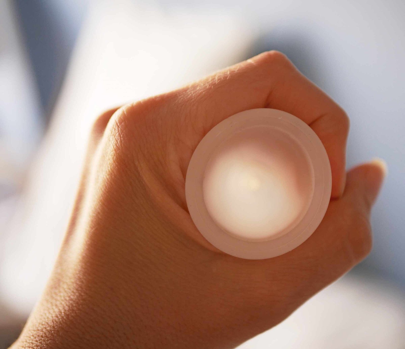 Mano que sostiene una copa menstrual de silicón translúcido