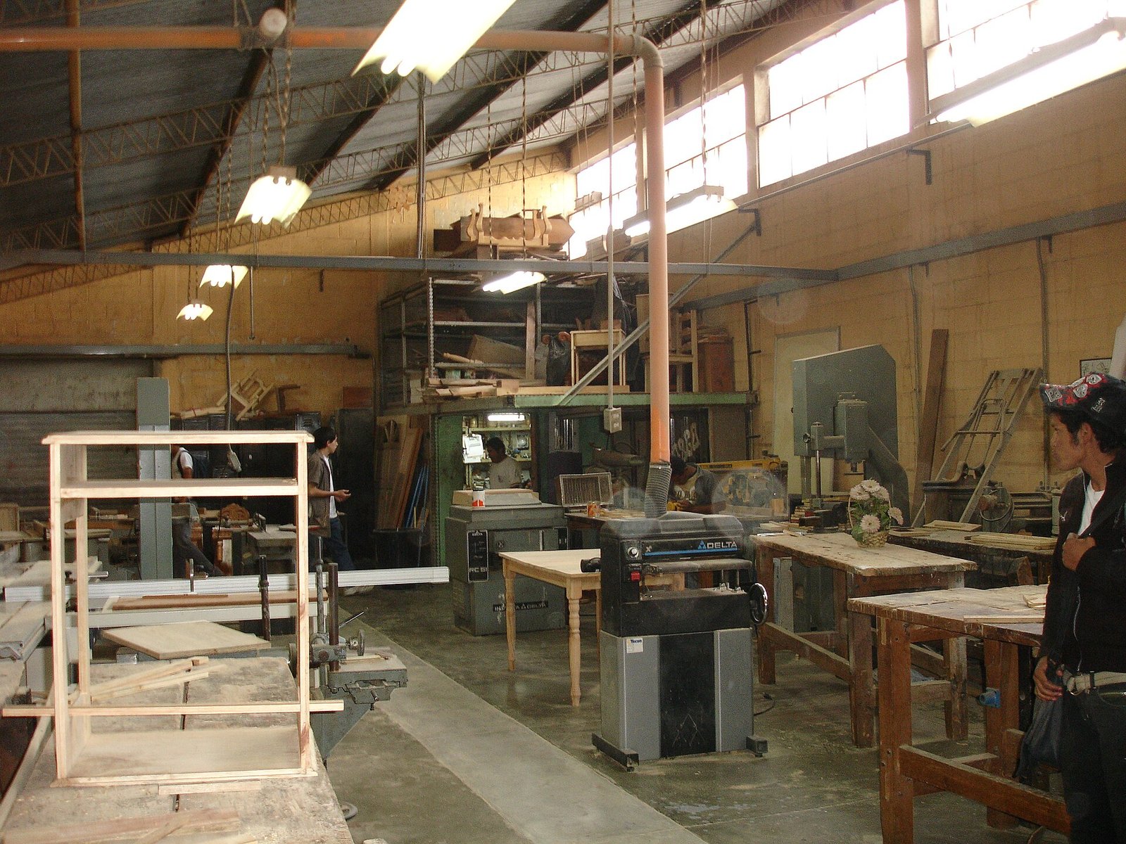 Taller de carpintería con bancos de trabajo, maquinaria para madera y un mueble en proceso