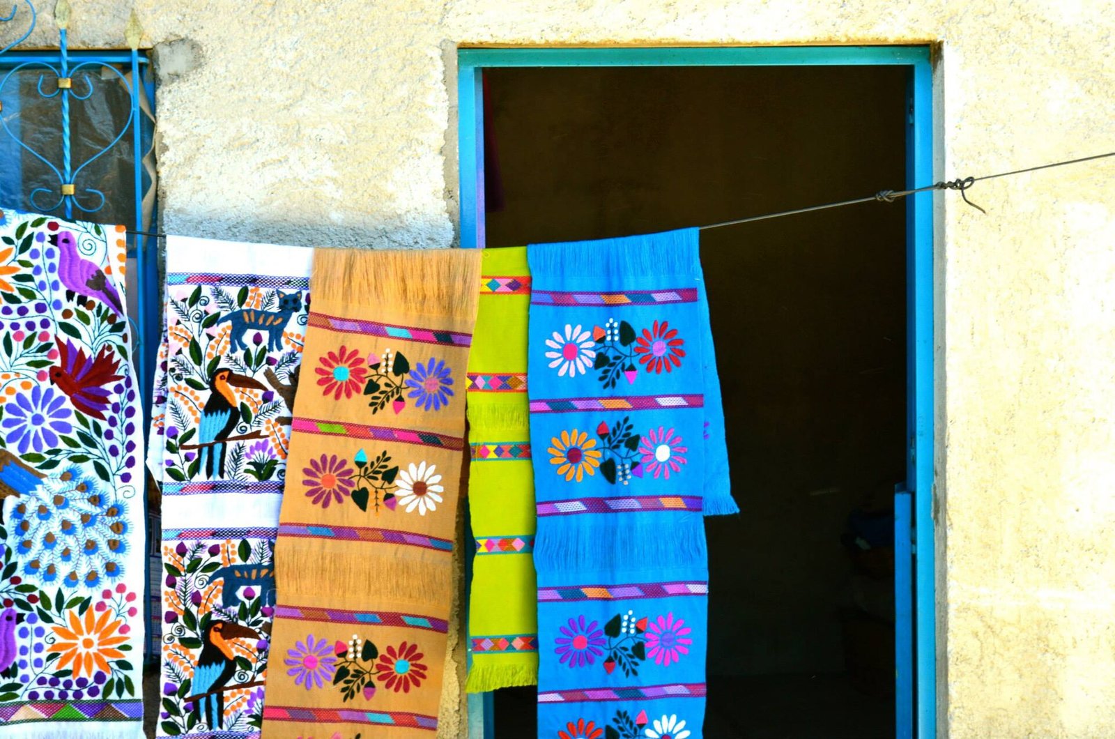Textiles bordados con flores y aves colgados a la entrada de una casa en Zinacantán, Chiapas