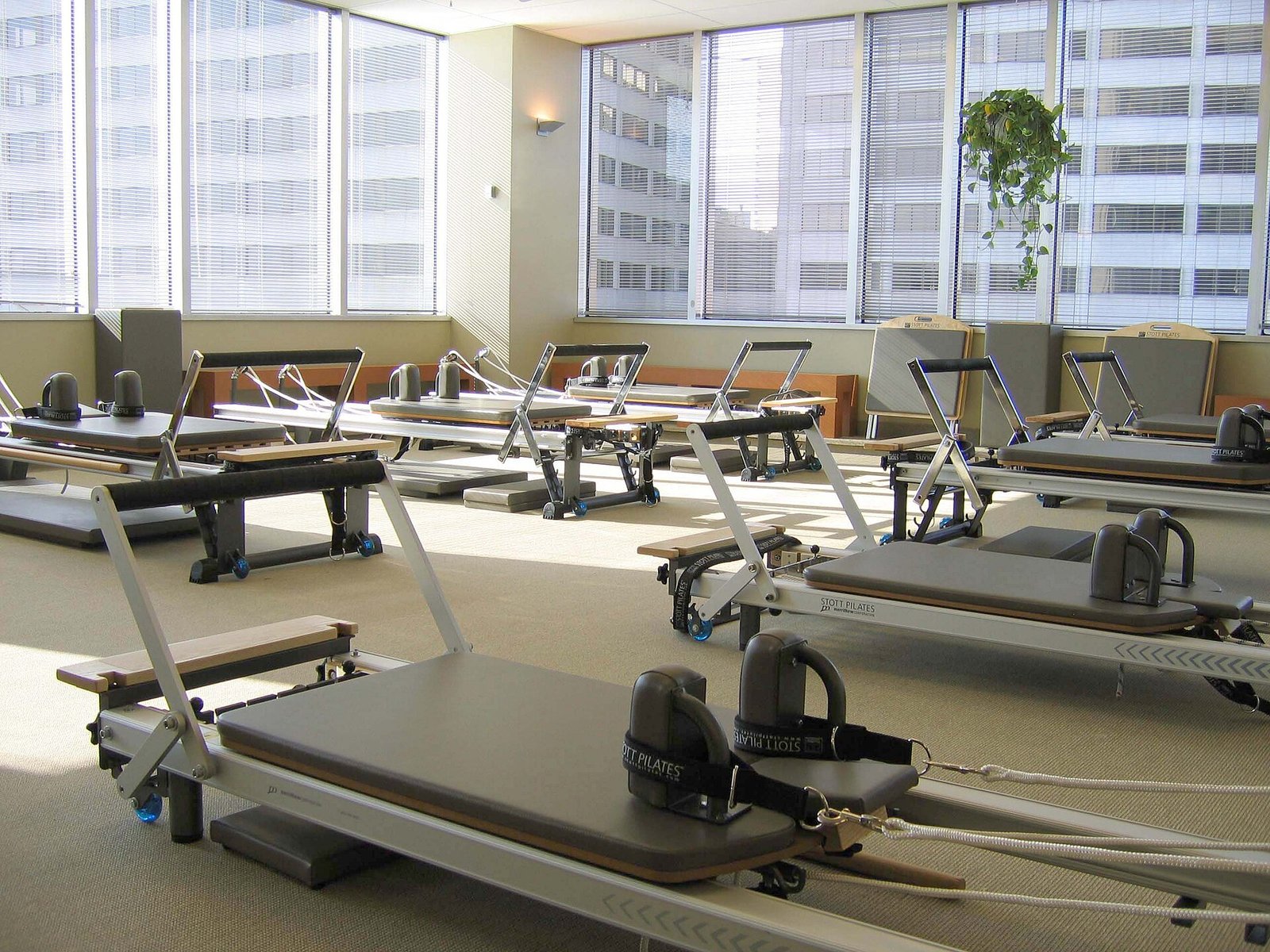 Sala de pilates con varias máquinas reformer alineadas frente a ventanales