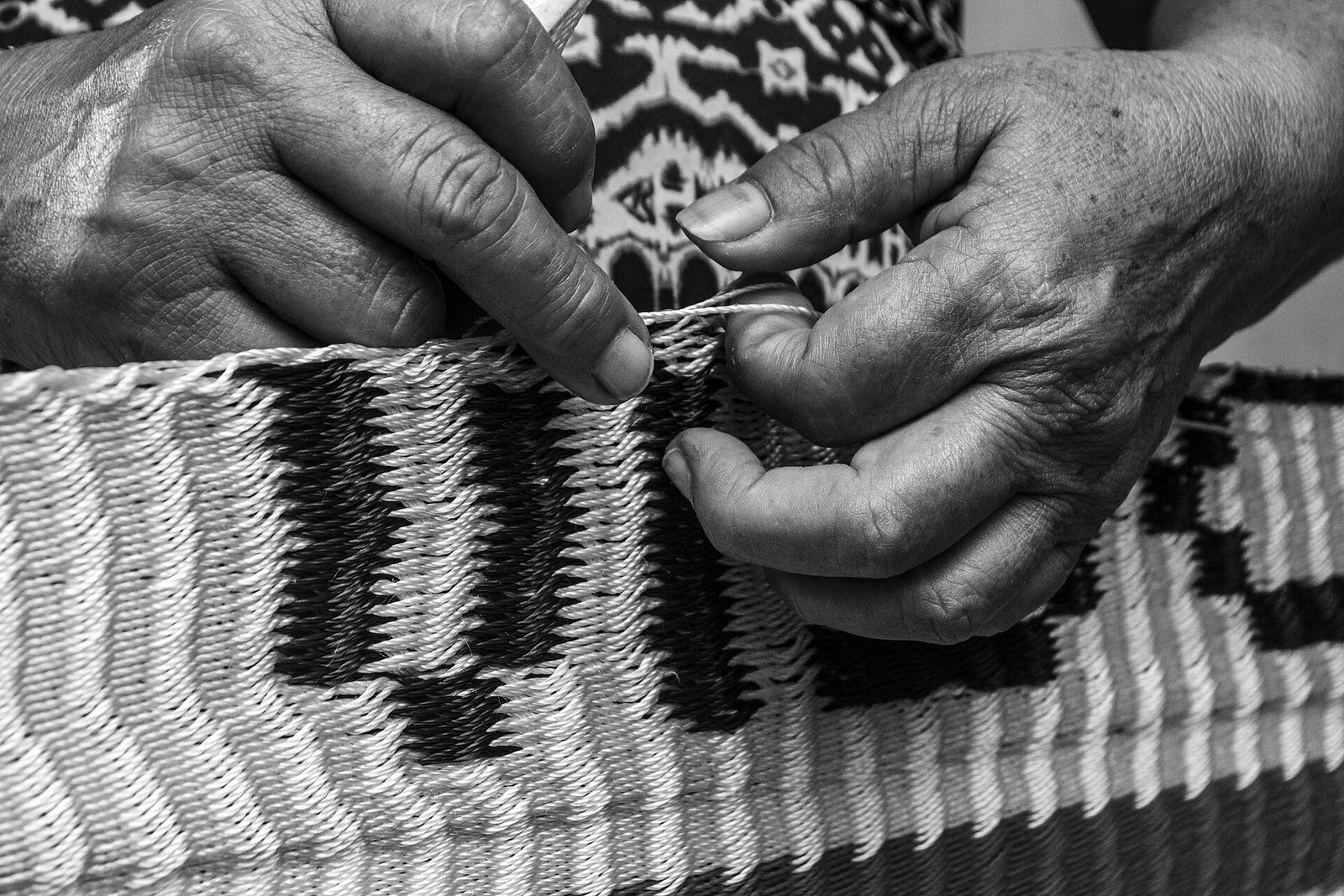 Manos de una artesana tejen una hamaca de hilo blanco y negro en Yucatán, en blanco y negro