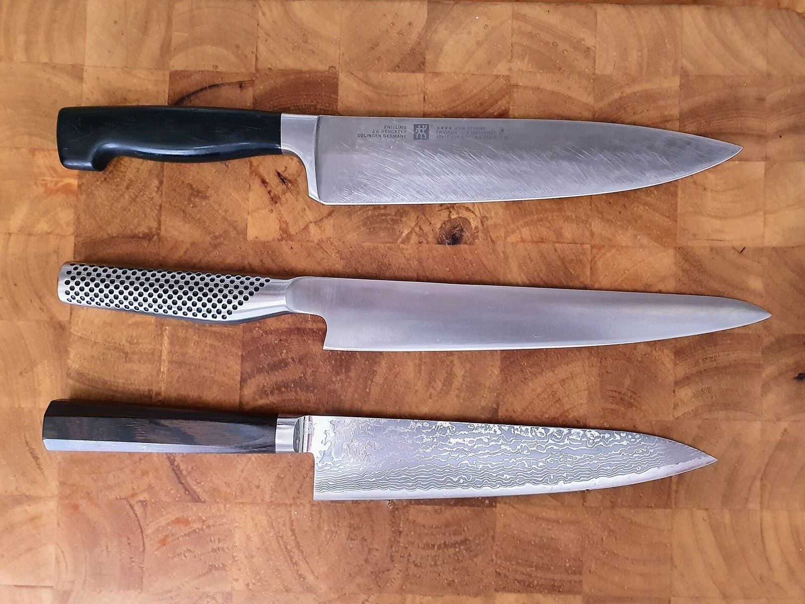 Tres cuchillos de cocina sobre una tabla de madera
