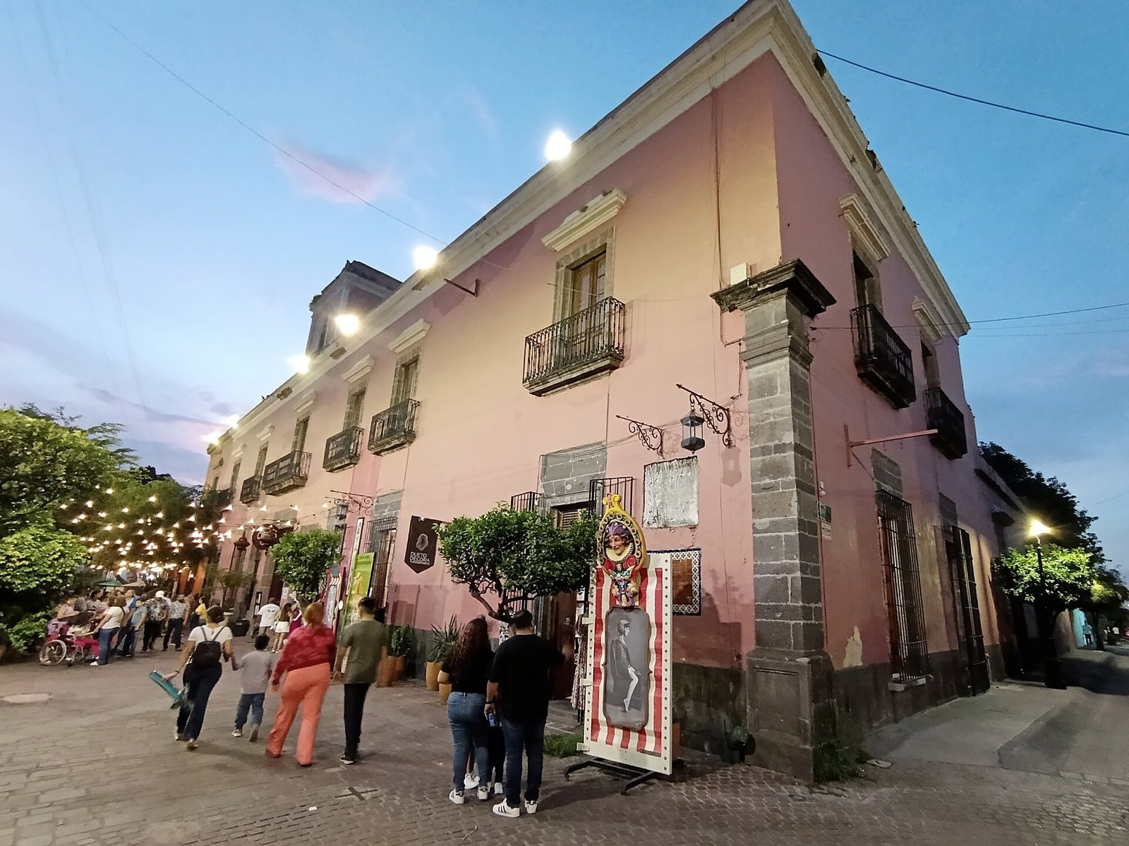 Calle del centro de Tlaquepaque al anochecer, con peatones y fachadas iluminadas
