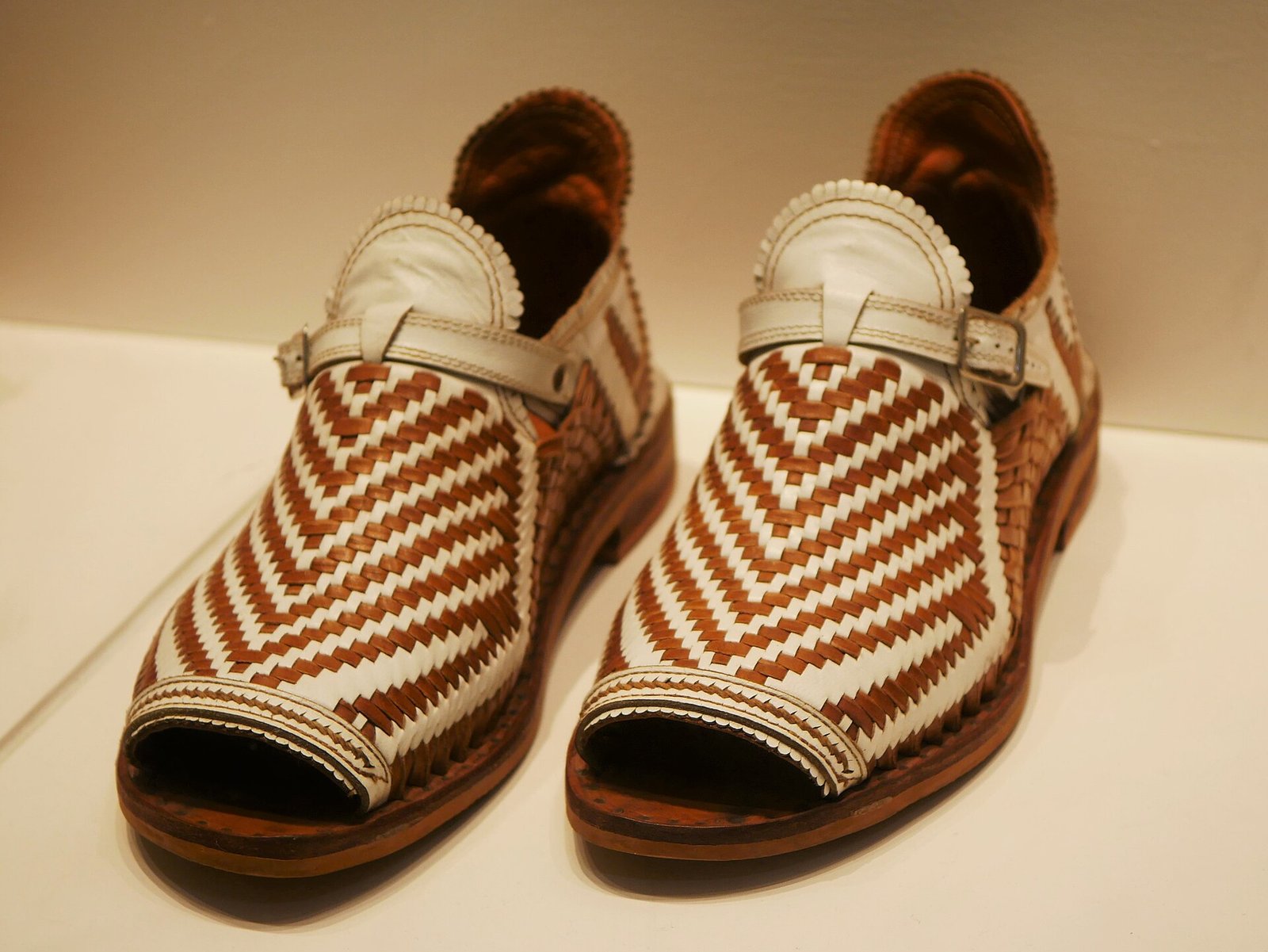 Par de huaraches de piel tejida en blanco y café exhibidos en el Museo de Arte Popular
