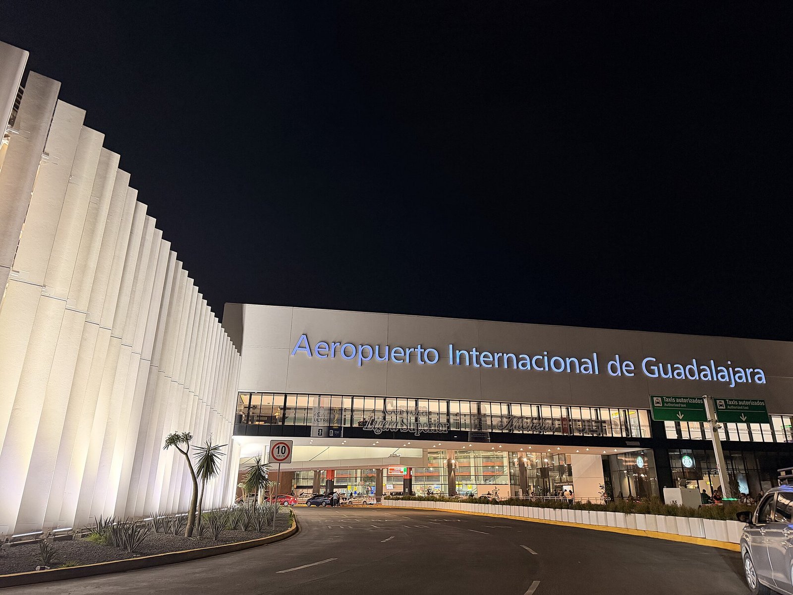 Fachada iluminada de noche de la terminal del Aeropuerto Internacional de Guadalajara