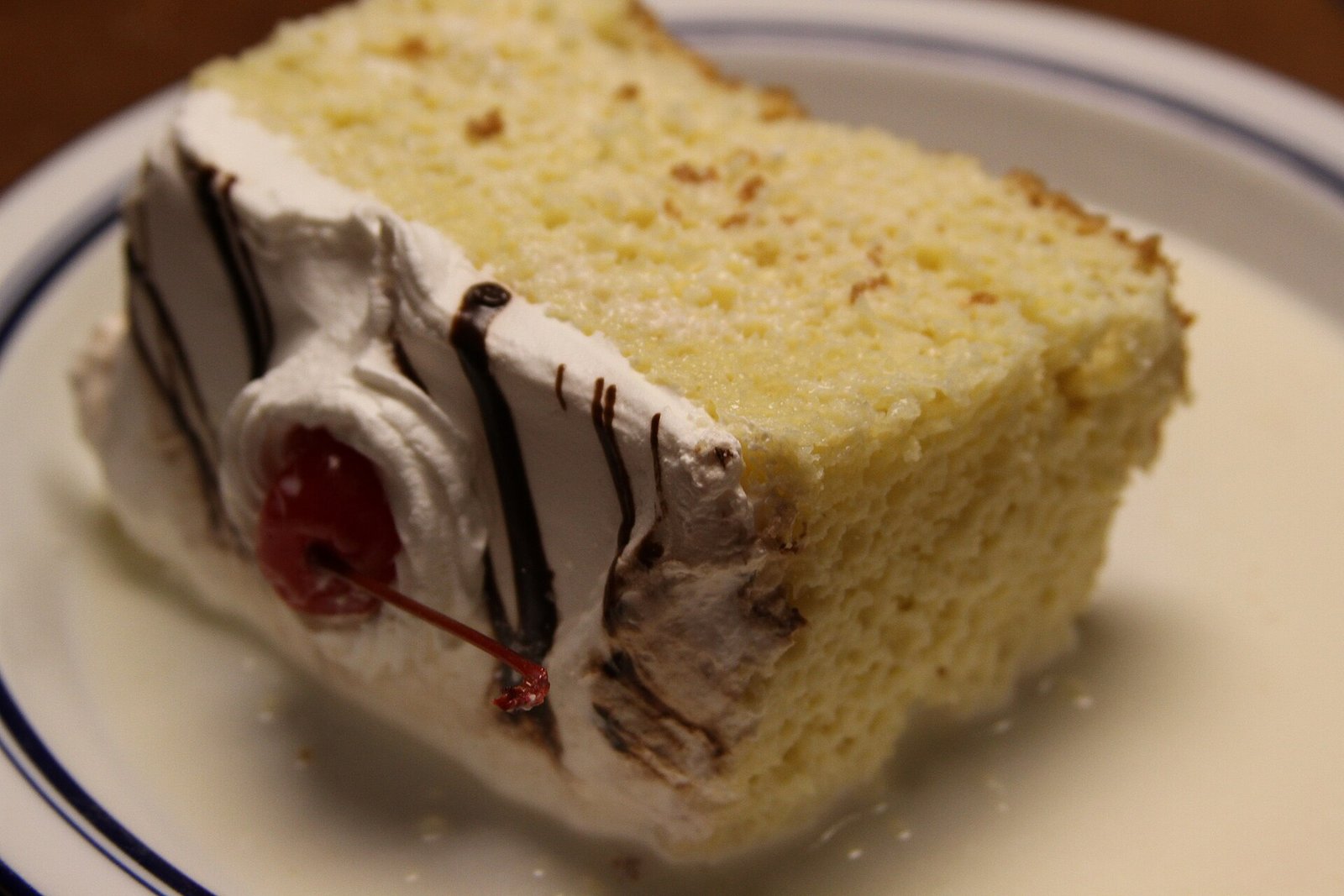 Rebanada de pastel tres leches con crema batida, chocolate y una cereza