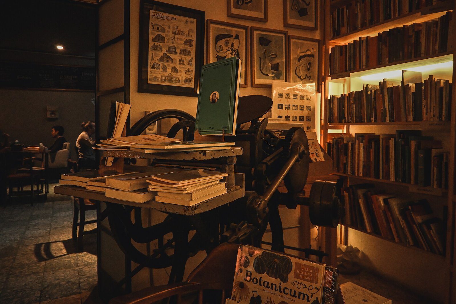 Interior de Impronta Casa Editora en Guadalajara, con libreros, una prensa antigua y grabados enmarcados