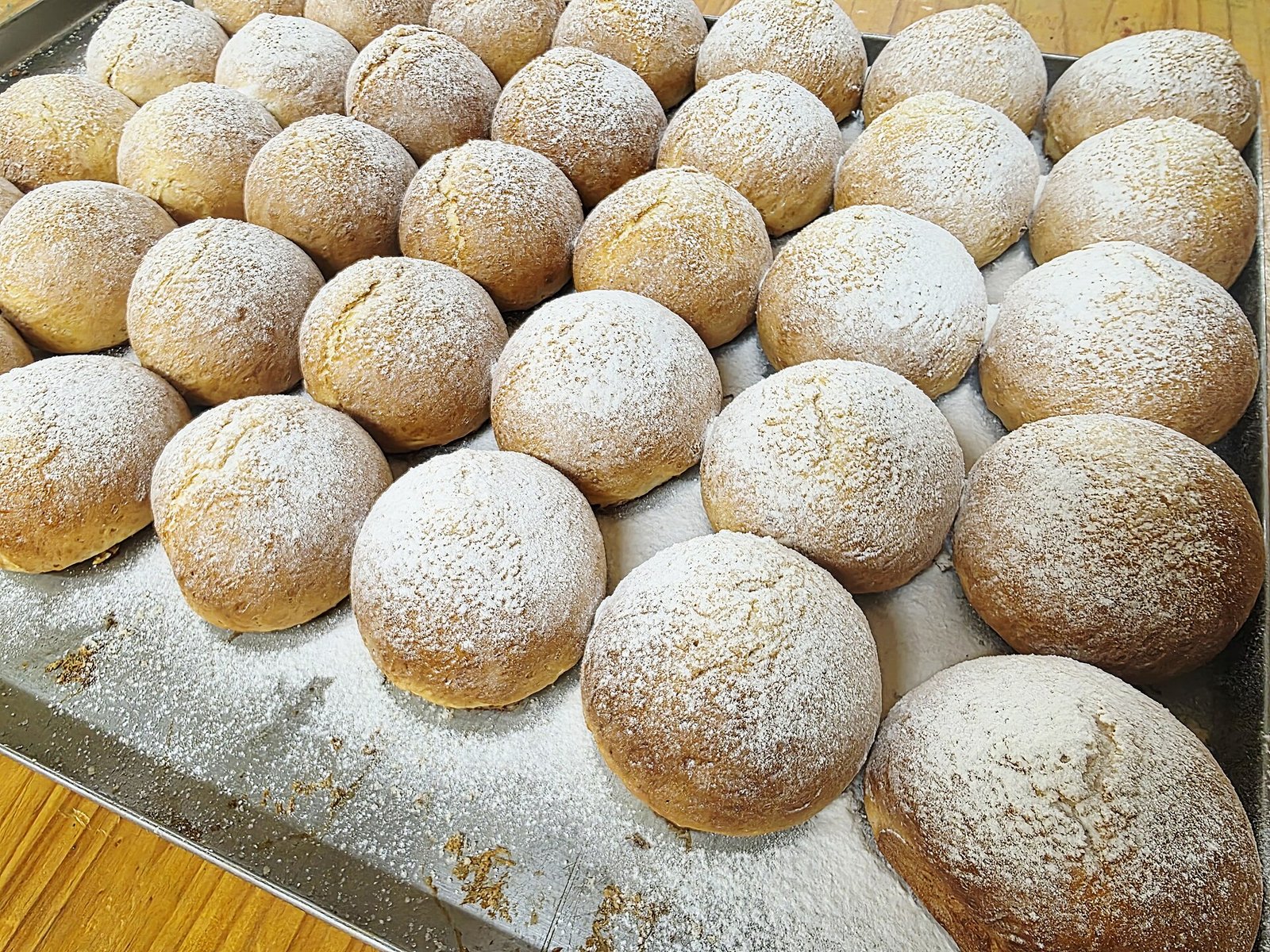 Bollos dulces de dulce de leche espolvoreados con azúcar en una charola de panadería