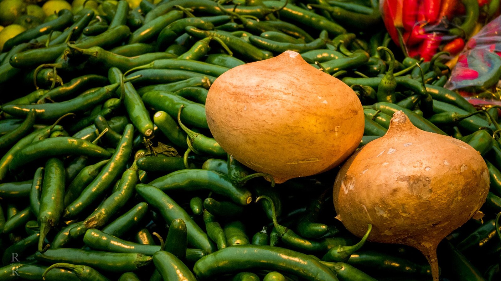 Jícamas sobre un montón de chiles verdes en un puesto de mercado