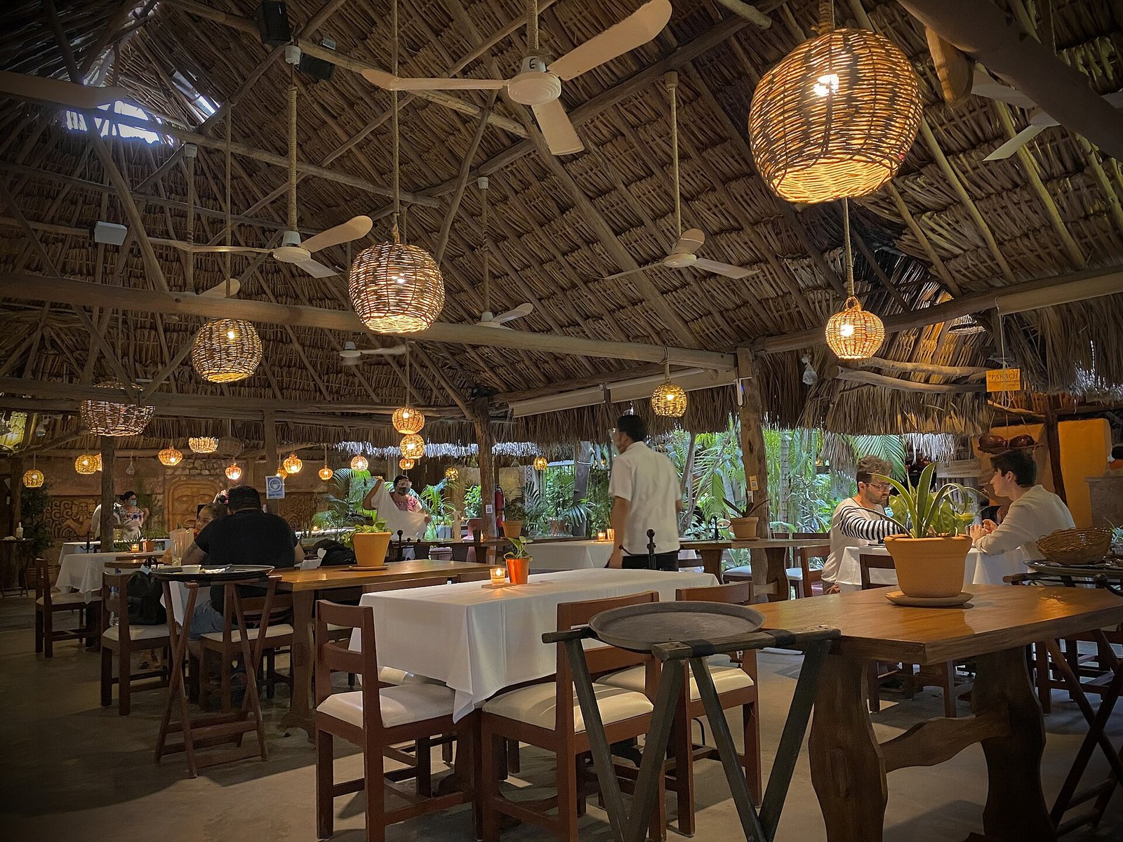 Comedor del restaurante Kinich en Izamal, bajo un techo de palapa con lámparas tejidas colgantes