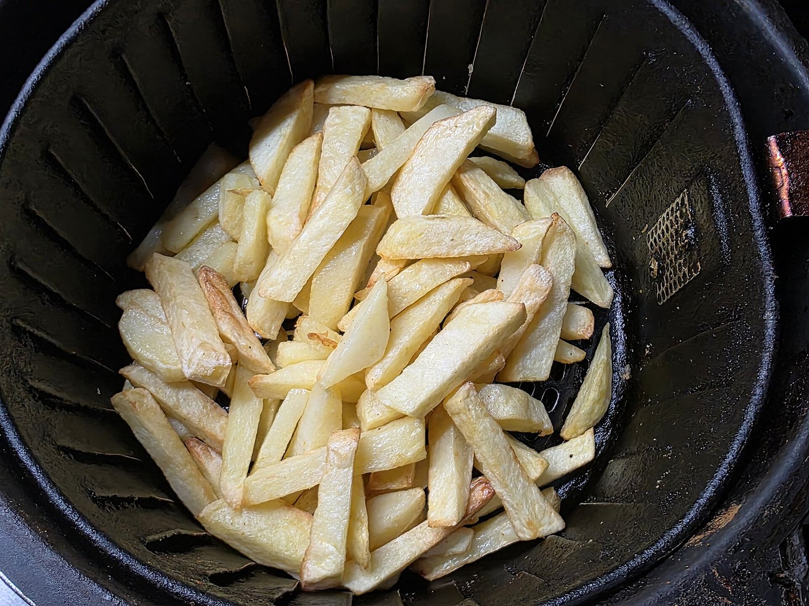 Papas fritas caseras dentro de la canasta de una freidora de aire