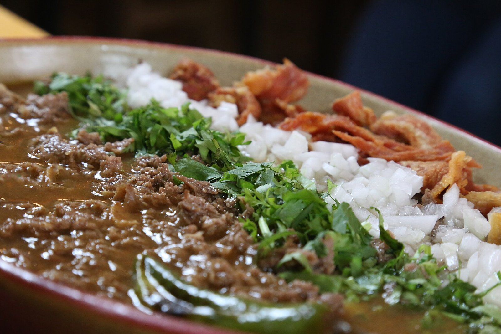 Plato de carne en su jugo con tocino frito, cebolla picada y cilantro