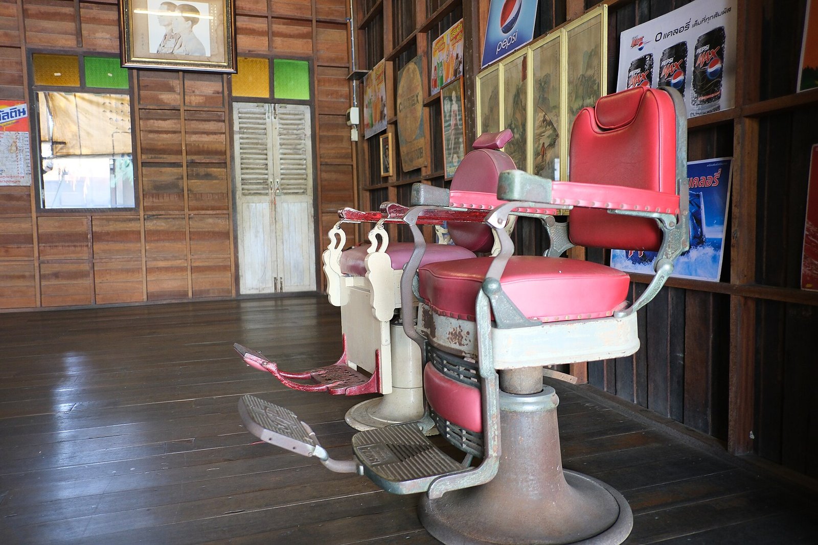 Sillones de barbero antiguos tapizados en rojo dentro de una barbería con muros de madera