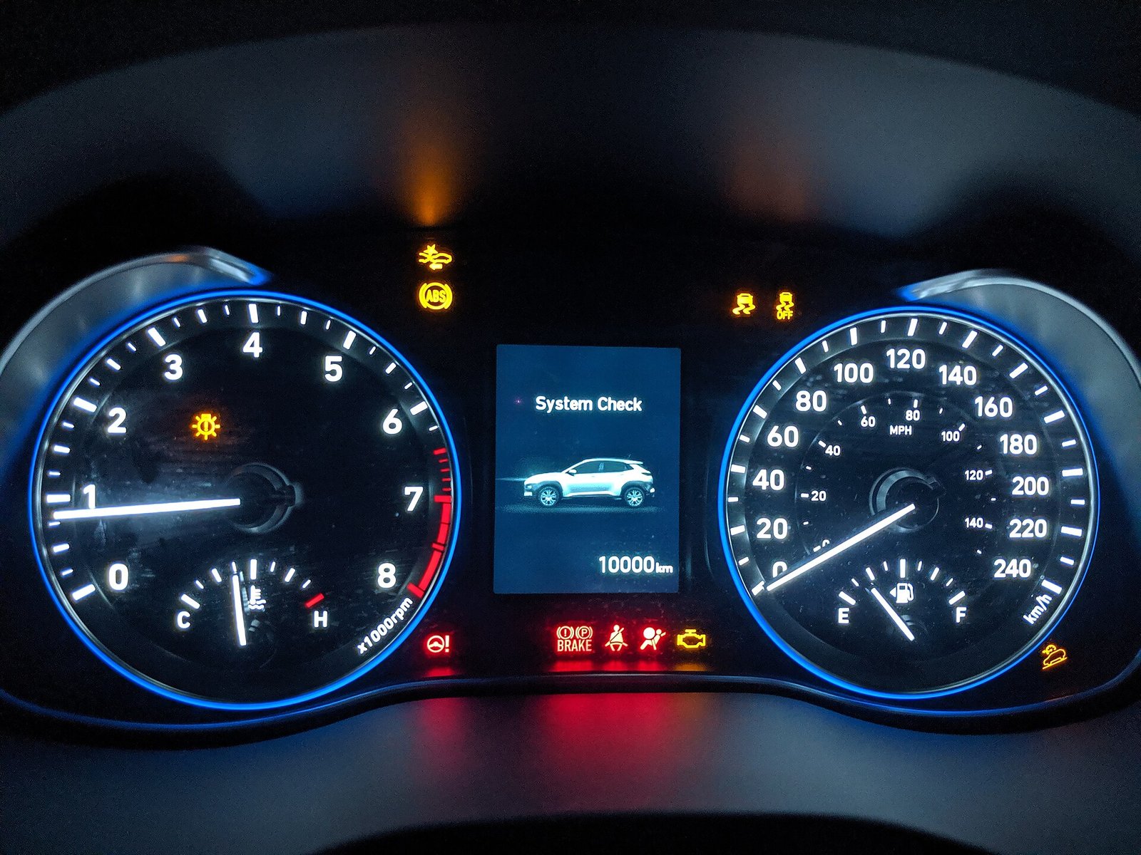 Tablero iluminado de un automóvil con el odómetro digital en 10,000 kilómetros
