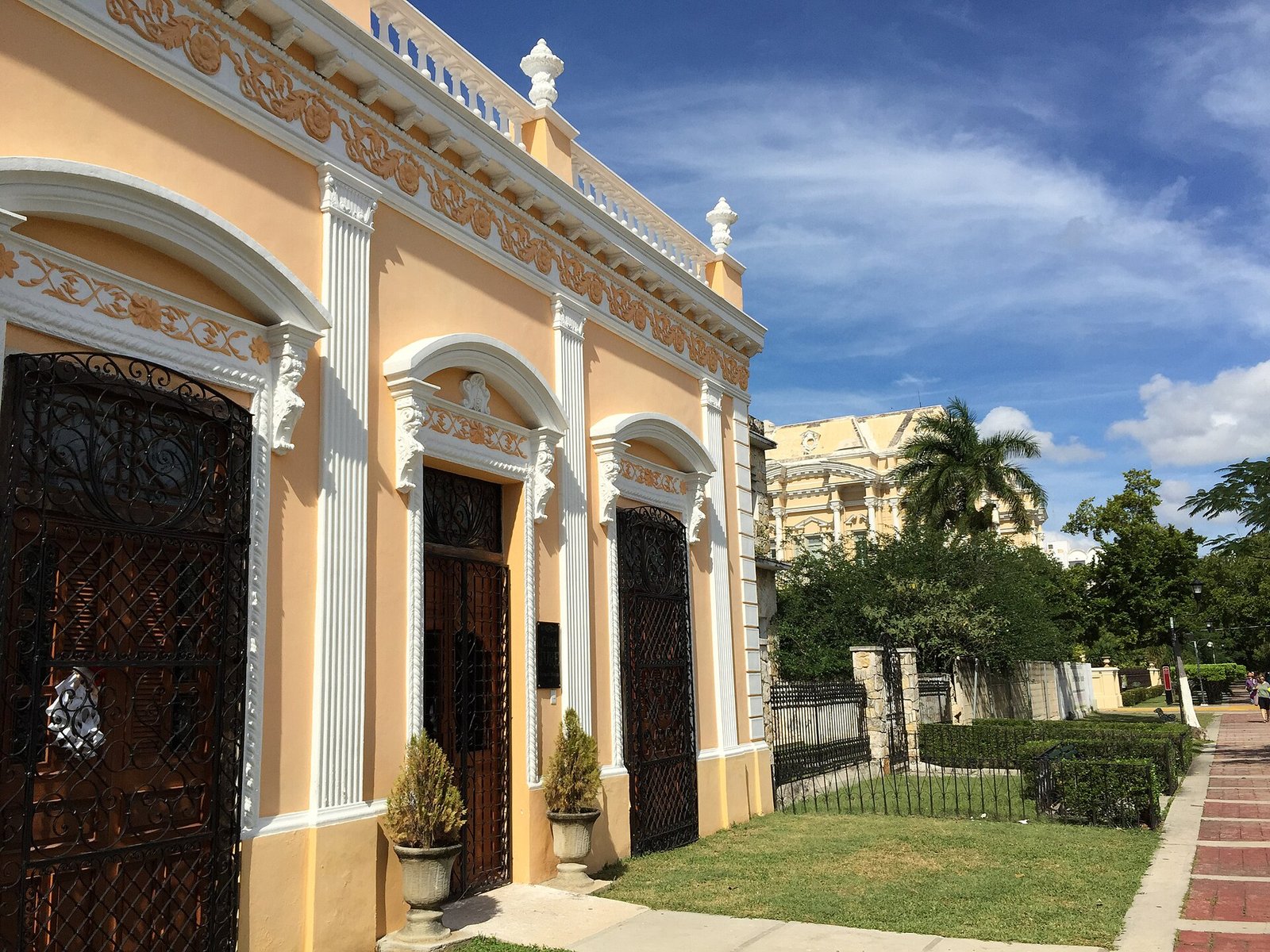 Fachada restaurada de una casona sobre el Paseo de Montejo, en Mérida, con rejas de hierro y jardín al frente