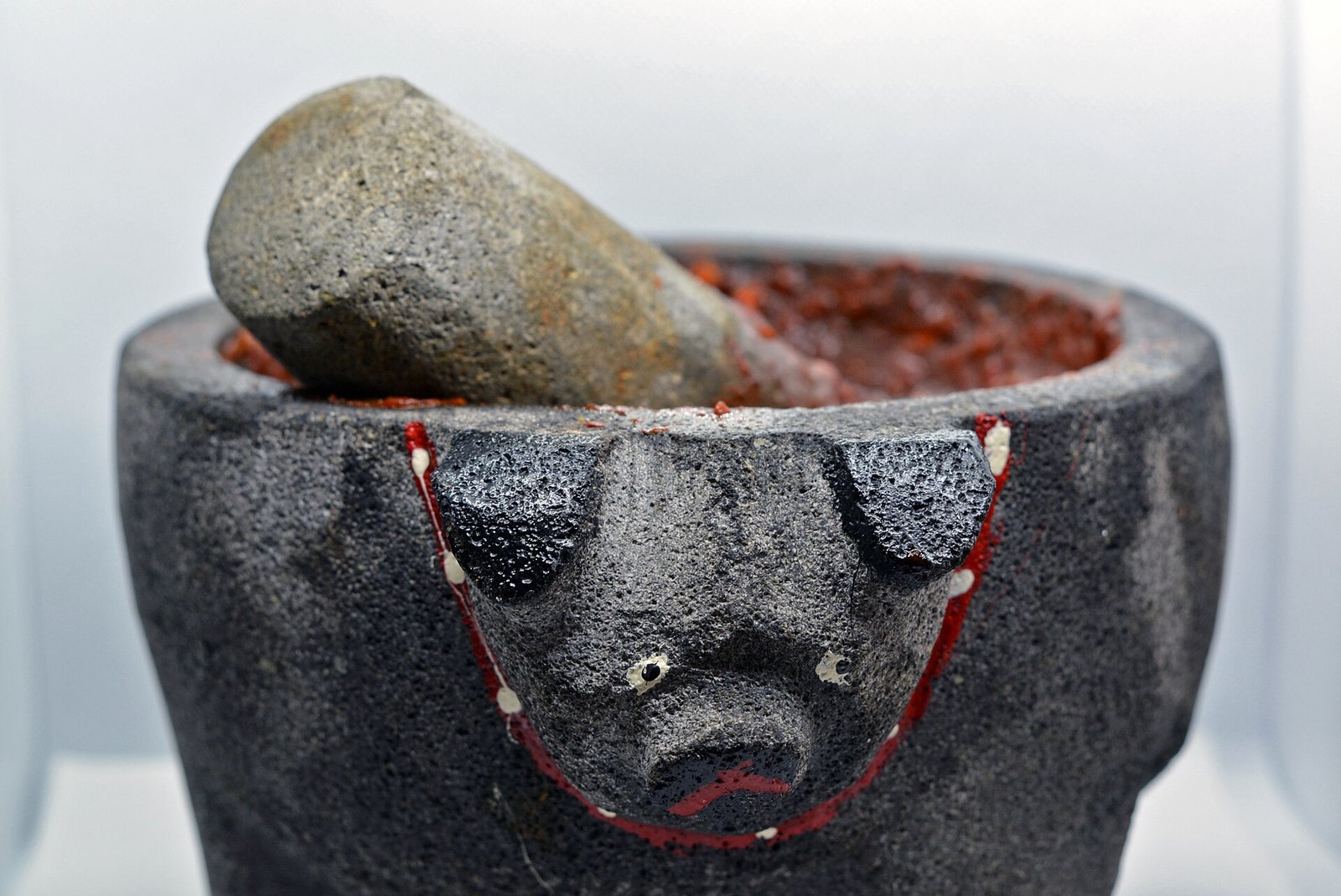 Molcajete de piedra volcánica con su tejolote y salsa roja