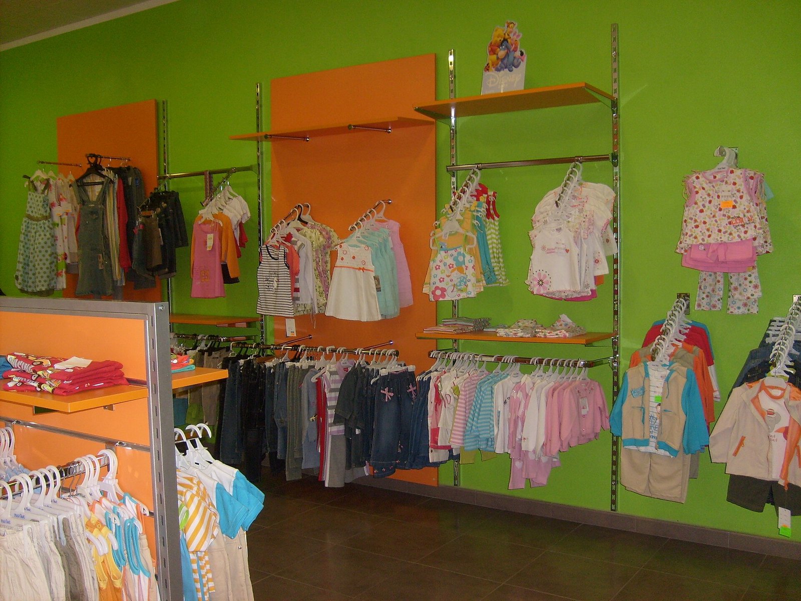 Ropa infantil colgada en ganchos y repisas en una tienda