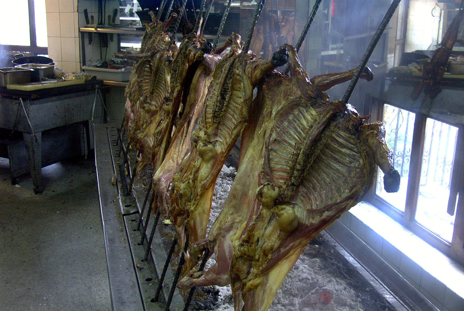 Cabritos abiertos en varas asándose al pastor sobre brasas en Monterrey