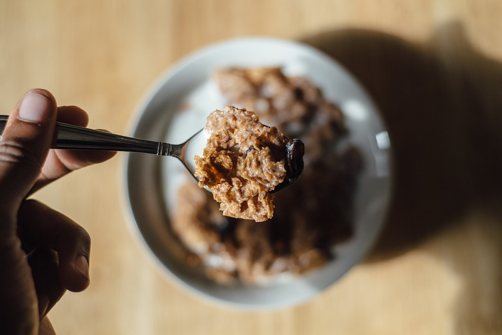 Cuchara con cereal de chocolate sobre un tazón blanco con leche
